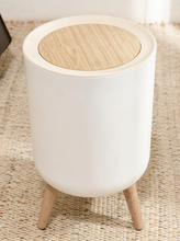 Load image into Gallery viewer, Modern white cylindrical trash can with round wood-look lid and three tapered wood-tone legs
