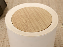 Load image into Gallery viewer, Modern white cylindrical trash can with round wood-look lid and three tapered wood-tone legs
