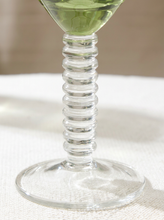 Load image into Gallery viewer, A close-up of a clear glass cocktail glass with a ribbed spiral stem and a round base, partially filled with a pale green liquid, set on a white textured surface.
