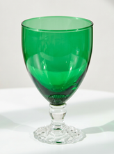 Load image into Gallery viewer, A green glass goblet with a clear glass stem and base, photographed on a white surface against a light gray background.

