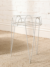 Load image into Gallery viewer, Vintage white painted metal plant stand with open circular wire frame, curved decorative supports, and four slender legs
