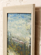 Load image into Gallery viewer, A framed landscape painting featuring an impressionistic blue and green sky over a forest, housed in a distressed off-white wooden frame and leaning against a textured brick wall.

