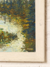 Load image into Gallery viewer, Close-up of a framed landscape painting showing textured brushstrokes in green, blue, yellow, and cream tones, with a distressed off-white frame against a white brick wall.
