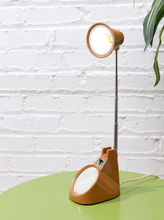 Load image into Gallery viewer, Vintage 1970s orange Space Age desk lamp with chrome adjustable stem, flared shade and circular mirror built into the base.
