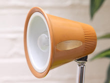 Load image into Gallery viewer, Close-up of the orange desk lamp's flared shade, white interior, bulb and side opening.
