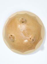 Load image into Gallery viewer, A top-down view of a round ceramic bowl with a glossy, warm beige finish and three small foot rings on the underside, set against a plain white background.
