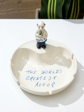 Load image into Gallery viewer, Vintage white ceramic ashtray with small hand-painted Gavin figurine and blue handwritten text reading The World’s Greatest Actor
