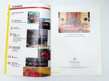 Load image into Gallery viewer, An open printed brochure or magazine spread showing printed text, page numbers, and several photos of red cars, photographed from above on a white surface.
