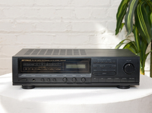 Load image into Gallery viewer, Vintage black Optimus AM/FM stereo receiver with rectangular digital tuner display, large volume knob, front control buttons, and vented top panel

