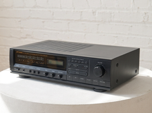 Load image into Gallery viewer, Vintage black Optimus AM/FM stereo receiver with rectangular digital tuner display, large volume knob, front control buttons, and vented top panel

