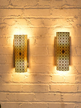Load image into Gallery viewer, Pair of vintage 1960s metal wall sconces with curved half-cylinder shades, repeating geometric cutout patterns, and rectangular wall mounts
