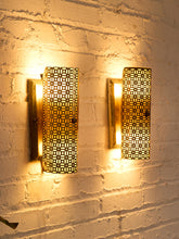 Load image into Gallery viewer, Pair of vintage 1960s metal wall sconces with curved half-cylinder shades, repeating geometric cutout patterns, and rectangular wall mounts
