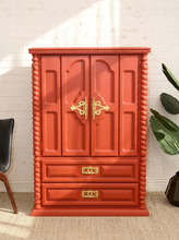 Load image into Gallery viewer, Vintage deep red painted armoire with double cabinet doors, ornate gold-tone handles, carved spiral side columns, raised decorative panels, and two lower drawers
