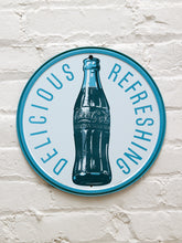 Load image into Gallery viewer, Round Coca-Cola metal advertising sign with silver background, blue Delicious Refreshing lettering, central glass Coke bottle illustration, and blue-green circular border
