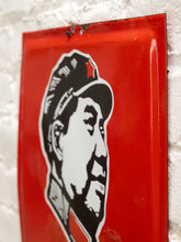 Load image into Gallery viewer, A vintage red enamel tin sign featuring a black and white stylized portrait of Mao Zedong, mounted on a white brick wall.
