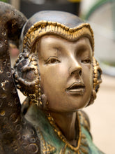 Load image into Gallery viewer, Close-up of a decorative sculpture or figurine with a stylized human face, wearing an ornate gold-trimmed headdress and teal-green garment details.
