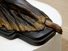 Load image into Gallery viewer, Close-up detail of a bronze sculpture showing a draped figure's leg and foot, mounted on a white cylindrical pedestal.
