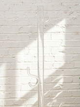 Load image into Gallery viewer, Vintage freestanding clear Lucite coat rack featuring a tall transparent cylindrical column, curved transparent hooks at different heights, and a round clear base.
