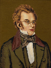 Load image into Gallery viewer, Vintage framed needlepoint portrait depicting a 19th-century gentleman with curly brown hair, round spectacles, a dark suit, and a patterned bow tie against a deep brown background, displayed in an ornate dark wood frame.
