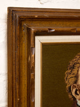 Load image into Gallery viewer, Close-up of an antique wooden picture frame with a cream inner mat and a needlepoint canvas showing part of a portrait.
