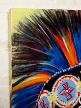 Load image into Gallery viewer, A close-up of a colorful painted canvas featuring a dramatic feather-like design in black, blue, orange, yellow, and white, with circular decorative motifs in the lower right, shown against a white textured wall.
