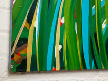 Load image into Gallery viewer, Abstract canvas painting featuring vertical brushstrokes of green, turquoise blue, yellow, black, and white, mounted on a white painted brick wall.
