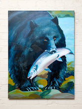 Load image into Gallery viewer, Image 1 of 8: Contemporary wildlife painting by Jean Bradley depicting a large black bear with amber eyes holding a silvery-pink salmon in its mouth, surrounded by green rocks and foliage against a soft blue background.
