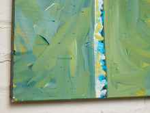 Load image into Gallery viewer, Abstract canvas painting with thick textured brushstrokes in shades of green, yellow, and blue, shown hanging on a white brick wall.
