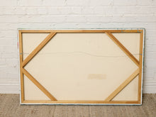 Load image into Gallery viewer, The back of a large framed canvas or art print, showing a light wood frame and support structure, leaning against a white brick wall on a textured beige floor.
