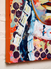 Load image into Gallery viewer, Image 5 of 8: Abstract canvas wall art featuring expressive brushstrokes in orange, cream, blue, black, pink, and yellow, shown hanging against a white painted brick wall.
