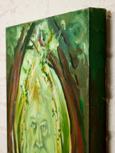 Load image into Gallery viewer, A close-up of a textured canvas painting featuring a stylized face with long flowing light green hair, surrounded by dark green, brown, and yellow organic shapes, shown hanging on a white brick wall.
