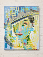 Load image into Gallery viewer, An abstract portrait painting of a woman wearing a hat, displayed on a white brick wall. The artwork features a mix of blue, yellow, green, and beige tones with textured brushstrokes and layered patterns.
