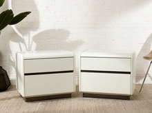 Load image into Gallery viewer, Pair of vintage postmodern white nightstands featuring glossy rectangular bodies, softly rounded corners, two handleless drawers each, and smoked translucent plinth bases.
