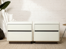 Load image into Gallery viewer, Pair of vintage postmodern white nightstands featuring glossy rectangular bodies, softly rounded corners, two handleless drawers each, and smoked translucent plinth bases.
