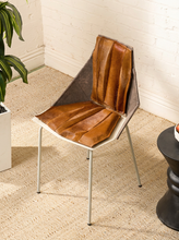 Load image into Gallery viewer, Image 3 of 16: A modern accent chair with a brown leather seat and pleated backrest, supported by slim silver metal legs, set on a beige textured rug in a room corner.
