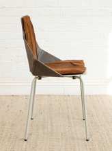 Load image into Gallery viewer, Image 5 of 16: A mid-century modern bar stool with a sculptural seat and back upholstered in brown leather and gray fabric, supported by a white metal frame, set against a white brick wall and a beige jute rug.

