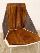 Load image into Gallery viewer, Image 7 of 16: A mid-century modern accent chair featuring a sculptural, angular backrest and seat upholstered in brown leather, with a white plastic shell and light gray metal legs, set against a white brick wall and beige rug.
