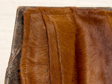 Load image into Gallery viewer, Image 12 of 16: Close-up of a brown faux fur or animal hair textile with stitched paneling and a dark gray fabric edge, shown against a light neutral background.
