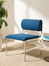 Load image into Gallery viewer, Image 1 of 14: Vintage dining chair featuring a navy blue upholstered seat, curved cylindrical padded backrest, open-back design, and slender chrome metal frame with angled legs.
