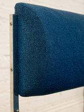 Load image into Gallery viewer, Image 13 of 14: Close-up of a blue upholstered chair or cushion with a curved edge and a visible silver metal support against a light off-white background.
