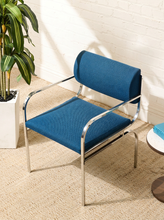 Load image into Gallery viewer, Image 3 of 15: Vintage dining armchair featuring a navy blue upholstered seat, curved cylindrical padded backrest, open-back design, polished chrome armrests, and slender angled metal legs.
