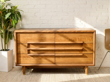 Load image into Gallery viewer, Image 1 of 16: Restored Guild of California mid-century modern six-drawer dresser featuring a warm honey-brown wood finish, three stacked drawers on each side, long sculptural horizontal wooden pulls, softly rounded cabinet edges, and short tapered legs.

