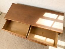 Load image into Gallery viewer, Image 16 of 16: A mid-century modern wooden console table with two open drawers, shown from an overhead angle against a white brick wall and textured rug.
