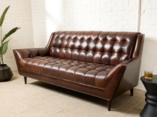 Load image into Gallery viewer, Image 2 of 13: Modern three-seater sofa featuring cognac brown leather upholstery, deep square button tufting across the backrest and seat, angular upholstered arms, and short tapered legs.
