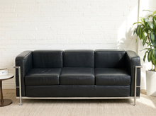 Load image into Gallery viewer, Image 1 of 14: Modern Le Corbusier-style three-seater sofa featuring black leather upholstery, three square seat and back cushions, wide padded arms, and an exposed polished chrome tubular frame.
