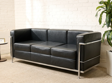Load image into Gallery viewer, Image 2 of 14: Modern Le Corbusier-style three-seater sofa featuring black leather upholstery, three square seat and back cushions, wide padded arms, and an exposed polished chrome tubular frame.
