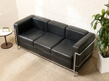 Load image into Gallery viewer, Image 3 of 14: Modern Le Corbusier-style three-seater sofa featuring black leather upholstery, three square seat and back cushions, wide padded arms, and an exposed polished chrome tubular frame.
