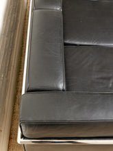 Load image into Gallery viewer, Image 9 of 14: Close-up of a black leather sofa cushion with a polished chrome metal frame, showing the texture of the leather and the reflective edge of the frame.
