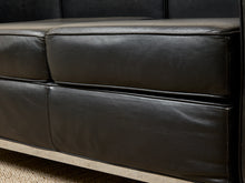 Load image into Gallery viewer, Image 11 of 14: Close-up of a dark brown leather sofa seat cushion with visible grain and stitching, showing part of the frame and a light-colored floor or carpet edge.

