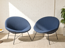 Load image into Gallery viewer, Image 17 of 17: Two modern blue upholstered accent chairs with black metal legs, positioned side-by-side in front of a white brick wall with sunlight streaming in.
